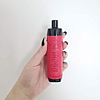 A hand holding a red vape device with black accents against a white background.