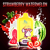 A yellow RandM Digital Box 12000 vape device with a monkey character wearing sunglasses and a hat, labeled "FUMOT," surrounded by splashes of milk, strawberries, and watermelon slices, with the text "STRAWBERRY WATERMELON" above.