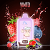 A purple vaping device with an illustration of a cartoon monkey wearing a cap, surrounded by splashes of red liquid and various fruits like strawberries, blueberries, raspberries, and blackcurrants. The device displays a digital screen with icons. The word "VIMTO" is at the top.