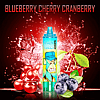 Blueberry Cherry Cranberry flavored vape device with cartoon-style ape character, surrounded by blueberries, cherries, and cranberry splash.