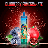 RandM Tornado 15000 vape device in blueberry pomegranate flavor, with an illustrated design of a monkey wearing a colorful hat, surrounded by blueberries and pomegranate fruit on a dark background.
