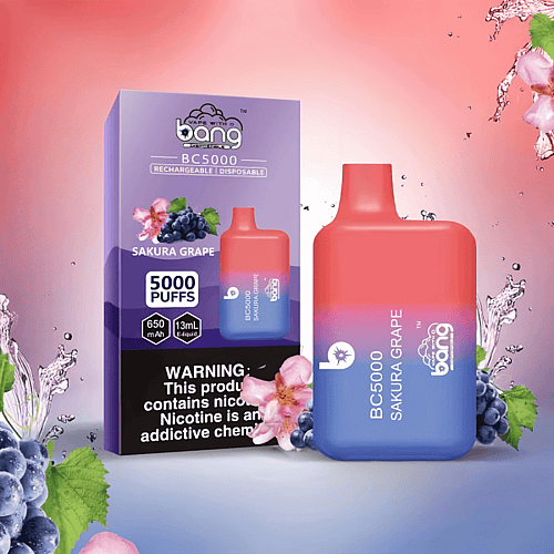 Un vaporizador desechable recargable etiquetado "Bang BC5000" en sabor a uva Sakura con 5000 bocanadas, 13 ml de e-líquido y batería de 650 mAh, exhibido junto a su empaque con detalles de uva y flores.