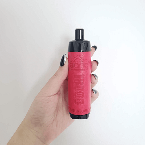 Une main tenant un appareil à vapotage rouge avec des accents noirs sur fond blanc.